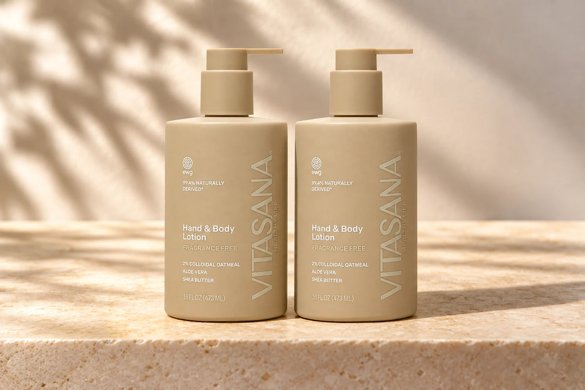 Two 16 fl oz Vitasana 2% Colloidal Oatmeal Fragrance Free Hand & Body Lotion bottles on a warm stone surface